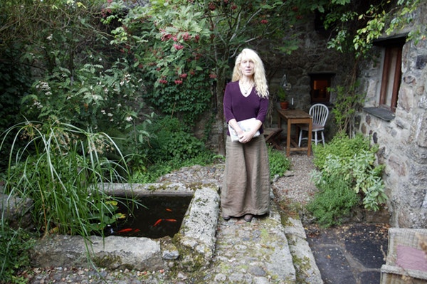 Terri Windling, holding a book, standing in a garden.