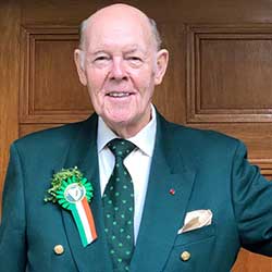 A balding white man in a green suit smiles for the camera